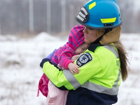 A paramedic carries a child to a waiting ambulance at the scene of a two-vehicle head-on collision on Wilton Grove Rd., east of Highbury Ave., in London on Sunday. Seven people were taken to hospital, none of the injuries life-threatening, following the crash between a taxi cab and an SUV. (CRAIG GLOVER, The London Free Press)