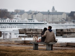 Jessie Leibman, from Vermont, rests on a bench along Kingston's waterfront with his friend Michelle on a snowy spring day during his visit to Kingston for the Easter weekend. (Annie Sakkab/For The Whig-Standard)