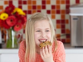7-year-old Mya Prehn, founder of Lunch Apeel bites into a snack in the kitchen. After being on Dragons' Den Prehn has teamed up with Mott's Fruitsations to help kids make better eating decisions. Photo Supplied