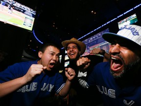 Toronto Blue Jays fans  Raymond Phan, Rami Davut, and Shakha Vasdani  are pictured at the Real Sports Bar  on Monday. (STAN BEHAL, Toronto Sun)