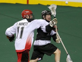 rpobert Church is checked by Roughnecks player Greg Harnett during a game in December in Calgary. (Mike Drew, QMI Agency)