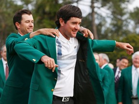 Bubba Watson (right) is presented with his green jacket by 2013 winner Adam Scott (left) after winning the Masters at the Augusta National Golf Club in Augusta, Ga. on Sunday, April 13, 2014. (Jim Young/Reuters/Files)