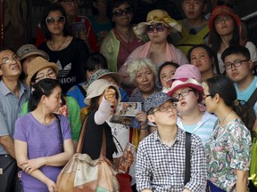 Chinese tourists listen to their guide as they visit at Wat Phra Kaeo (Emerald Buddha Temple) in Bangkok, March 23, 2015. REUTERS/Chaiwat Subprasom