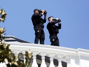 Members of the White House Counter Assault Team watch the area around the White House from the roof of the building during the annual Easter Egg Roll in Washington, D.C., April 6, 2015. (GARY CAMERON/Reuters)