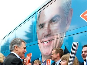 A large portrait of Alberta Tory leader Jim Prentice looms over him as he shakes hands with supporters before getting back onto his campaign bus after he announced a provincial election at the Crestwood Hall in Edmonton, Alta., on Tuesday April 7, 2015. Perry Mah/Edmonton Sun/QMI Agency