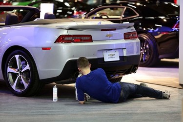 A worker cleans the exhaust pipes of Chevolet Camaro at the 2015 Edmonton Motorshow at the Edmonton Expo Centre in Edmonton, Alberta on Tuesday, April 7, 2015. Perry Mah/Edmonton Sun/QMI Agency