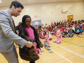 Jeremy Dias helps Diana Sauveur, a Grade 2 student at W.E Gowling Public School, tries on the 'Gay Sweater' at the school's International Day of Pink anti-bullying assembly on Apr. 8, 2015 in Ottawa. The sweater is knitted from clippings of hair donated by hundreds of gay, lesbian, bisexual and transgendered Canadians.  Andrew Meade/ Ottawa Sun
