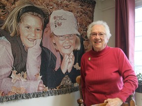 Reta Thompson, known at Fairfield Elementary School as Aunt Reta, is being honoured for her volunteer work with the school's hot dog lunch program. She is standing in front of a wall hanging showing her great nieces Rebecca and Victoria Thompson. (Michael Lea/The Whig-Standard)