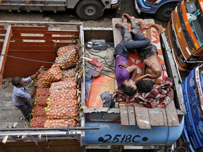 A worker unloads sacks of vegetables as men sleep on top of a truck at a wholesale vegetable market in the western Indian city of Ahmedabad in this July 14, 2014 file photo. . REUTERS/Amit Dave/Files