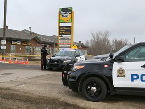 An Edmonton Police Service constable stands guard near evidence is covered on 115 Ave., at 215 St.,  in Edmonton, Alta., on Tuesday April 7, 2015. It is reported that gunfire erupted around 9 p.m. on April 6th., in a parking lot in the area of 215 Street (Winterburn Road) and 115 Avenue. Shortly after, a man was found dead 11 km north on a road outside the Nevada Place Apartments in St. Albert. Tom Braid/Edmonton Sun