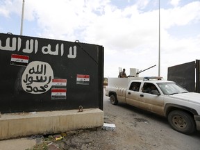 Iraqi security forces ride a vehicle past a wall painted with the black flag commonly used by Islamic State militants, near former Iraqi president Saddam Hussein's palace in Tikrit  April 1, 2015.  REUTERS/Thaier Al-Sudani
