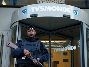 A French police officer stands guard in front of the main entrance of French television network TV5Monde headquarters in Paris April 9, 2015. French broadcaster TV5Monde was working on Thursday to regain control over its 11 channels and websites after an "extremely powerful" cyber attack claimed by the supporters of the Islamic State, its director said.  REUTERS/Benoit Tessier