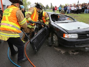 Firefighters remove a car door in a mock car crash to show students the dangers of drunk driving at St Cecellia School in Edmonton, Alta., on Wednesday, May 28, 2014.  Perry Mah/ Edmonton Sun