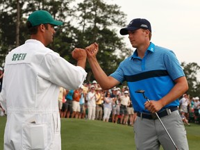 Jordan Spieth (right) taps fists with his caddie Michael Greller after finishing the 18th hole during the first round of the Masters at Augusta National Golf Course in Augusta, Ga., on Thursday, April 9, 2015. (Phil Noble/Reuters)