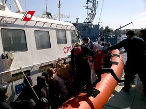 In this handout videograb released by the Italian coast guards (Guardia Costiera) migrants arrive  in the port of Lampedusa on a boat of the Guardia Costiera following a rescue operation off the coast of Sicily, on April 5, 2015. (AFP PHOTO/ GUARDIA COSTIERA