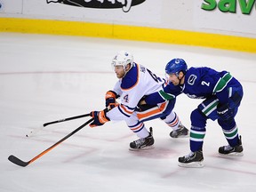 Jan 27, 2014; Vancouver, British Columbia, CAN; Vancouver Canucks defenseman Dan Hamhuis (2) reaches across Edmonton Oilers forward Taylor Hall (4) during the second period at Rogers Arena. Mandatory Credit: Anne-Marie Sorvin-USA TODAY Sports