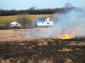 Prince Edward County firefighters are busy fighting a stubborn blaze in a Sophiasburgh marsh early Saturday morning, April 11, 2015. The fire broke out around 2 a.m. in the marsh between County Road 15 and Big Island, east of the causeway. Above, firefighters remained on scene well into the day, fighting small pockets of flames spread out over the huge marsh area. - Bruce Bell/Belleville Intelligencer/QMI Agency