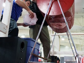 Kinsmen Club of Kingston members Sean Allen, foreground, and Graham Forsythe load the more than 5,400 tickets into the draw barrel at the Kingston Home Show in Kingston on Sunday. (Steph Crosier/The Whig-Standard)