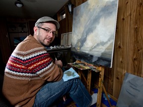 Artist Jamie Jardine works on a painting of alien flying saucers attacking tall ships in his home studio. (DEREK RUTTAN, The London Free Press)