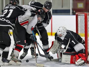 Akwesasne Wolves' Tylor Alguire (21) and Evan Mantha (12) attempt to ward off Tyler Turcotte of the Gananoque Islanders prior to goaltender Logan Gauthier smothering the loose puck during the third period in Gananoque. (Postmedia Network file photo)