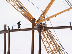 A construction worker walks across a steel girder at the Rogers Place arena construction site, in Edmonton Alta., on Monday March 23, 2015. David Bloom/Edmonton Sun