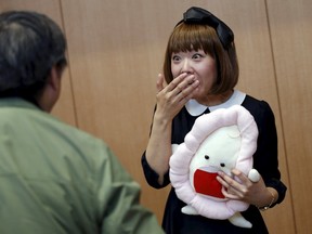 Japanese artist Megumi Igarashi, right, known as Rokudenashiko, holding her vagina-inspired artwork, reacts to a photographer after a news conference following a court appearance in Tokyo on April 15, 2015. (REUTERS/Toru Hanai)
