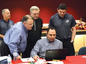 Sudbury Wolves assistant GM Ken MacKenzie (left), head scout Andrew Shaw, GM Blaine Smith and head coach Dave Matsos gather around longtime Wolves scout Sean Howard in the team's draft room at Sudbury Community Arena during Saturday's OHL Priority Selection.