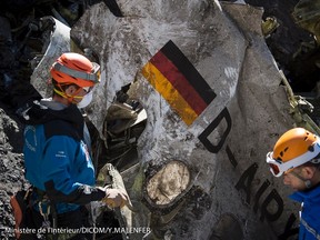French gendarmes, seen in this picture made available to the press by the French Interior Ministry April 1, 2015, work near debris from wreckage showing a German flag at the crash site of an Airbus A320, near Seyne-les-Alpes.  The German pilot, Andreas Lubitz, 27, who crashed a plane in the French Alps last week, killing 150 people, told officials at a Lufthansa training school in 2009 that he had gone through a period of severe depression, the airline said on Tuesday.  REUTERS/French Interior Ministry