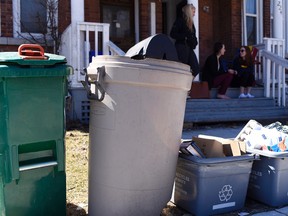 Fourth-year Queen's University students Michelle Woitowich, Claire McKenna and Laura Krieger spend the afternoon on their front porch with numerous garbage and recycling bins at the end of the lot on University Avenue Tuesday afternoon. (James Paddle-Grant/For The Whig-Standard)