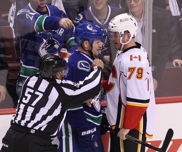 An official breaks up a confrontation between Vancouver Canucks Derek Dorsett Calgary Flames' Michael Ferland during the first period of Game 1 in a first-round NHL playoffs series at Rogers Arena on April 15, 2015. (Carmine Marinelli/Postmedia Network)
