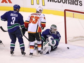 Vancouver Canucks’  goalie Eddie Lack (right) looks back after getting scored on by Calgary Flames' Kris Russell (not seen) as Vancouver Canucks’ Kevin Bieksa and Calgary Flames'  Sam Bennett look on during the third  period of Game One in a first-round NHL Stanley Cup playoffs series in Vancouver, B.C. on Wednesday April 15, 2015. Carmine Marinelli/Postmedia Network