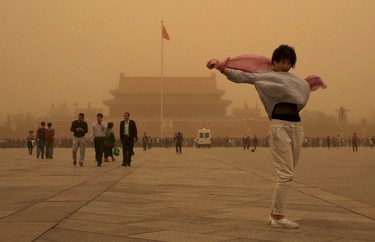 A tourist gestures as she poses for a photograph at Tiananmen Square during a sandstorm in Beijing, April 15, 2015. A sandstorm swept through China's northern regions on Wednesday, shrouding cities in dust and slowing down road traffic. (REUTERS/China Daily)
