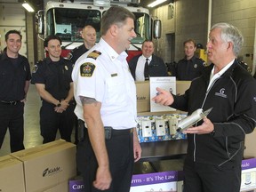 John Gignac, right, who has been promoting the use of carbon monoxide detectors since the death of his niece and her family in 2008, brought 100 of the detectors to Kingston Fire & Rescue's Woodbine Road station Friday morning and presented them to Deputy Chief Don Corbett, left. FRI., APR. 17, 2015 KINGSTON, ONT. MICHAEL LEA THE WHIG STANDARD