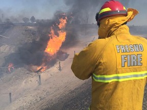 A firefighter watches the blaze after a gas line exploded near Fresno, California April 17, 2015. A construction crew accidentally ruptured a natural gas transmission line on Friday in Fresno, California, sparking an explosion and fire that injured up to 15 people, at least one of them critically, a fire department spokesman said. The 12-inch (30-cm) pipeline, belonging to Pacific Gas & Electric Corp, was struck by a backhoe near state Highway 99, unleashing a fireball that injured members of the construction team and a prison inmate crew in the vicinity, spokesman Peter Martinez said. (REUTERS/Fresno Fire Department/handout via Reuters)