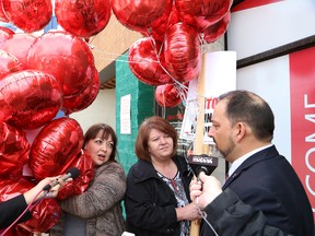 Natalie Mehra, left, executive director of Ontario Health Coalition, and Anne Marie MacInnis, president of Mine Mill Local 598/Unifor, present petition balloons to Sudbury MPP Glenn Thibeault during a rally against hospital cuts outside Thibeault's office in Sudbury, Ont. on Friday April 17, 2015. John Lappa/Sudbury Star/Postmedia Network