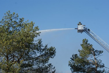 Firefighters spray water from an aerial ladder in an attempt to douse the flames at a four-alarm apartment complex fire in West Ottawa on Saturday. Strong winds swept the flames quickly through the upper floor of the Deerfield Dr. townhome complex. (MICHAEL MILLER Submitted Image / Ottawa Sun)