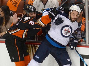 Chris Thorburn (22) gets bashed by Clayton Stoner in Anaheim on Saturday. (JAYNE KAMIN-ONCEA/USA TODAY Sports)