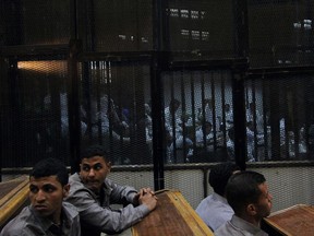 Egyptian defendants sit behind bars during their trial at a police institute in the outskirts of Cairo on April 19, 2015. An Egyptian court sentenced 11 football fans to death after a retrial over a 2012 stadium riot in the canal city of Port Said that left 74 people dead. AFP PHOTO / STR