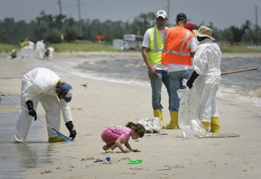 A girl plays in the sand as workers pick up oil balls from the Deepwater Horizon oil spill in Waveland, Mississippi July 7, 2010. REUTERS/Lee Celano