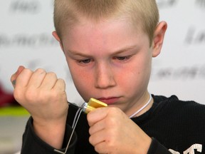 Gavin Micks, 8, picks a three-pin lock as part of a recent Maker Bus hands-on creative class at Vibrafusion labs on Clarence St. in London. (MIKE HENSEN, The London Free Press)