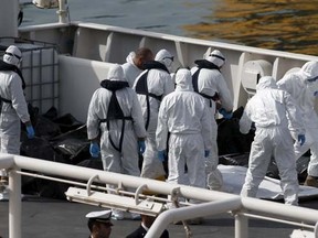 Italian coastguard and Armed Forces of Malta personnel in protective clothing stand near the bodies of dead immigrants on the ship Bruno Gregoretti in Senglea in Valletta's Grand Harbour, April 20, 2015. REUTERS/Darrin Zammit Lupi