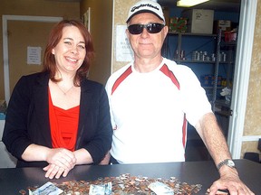 The Salvation Army's Gerri St. Pierre, left, accepts a donation of coins and bills from Jim Aubie. Aubie, a retired postal worker, collected the money over the past 15 years as he walked along his route. (DAVID GOUGH/Postmedia Network)