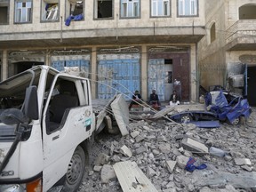 People sit next to trucks damaged by an air strike on a nearby Scud missile base in Yemen's capital Sanaa April 20, 2015. An air strike on a Scud missile base in the Yemeni capital Sanaa caused a big explosion that blew out windows in homes, killing seven civilians and wounding dozens, medical sources told Reuters. REUTERS/Khaled Abdullah