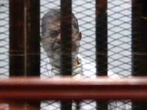 Former Egyptian President Mohamed Mursi sits behind bars with other Muslim Brotherhood members at a court in the outskirts of Cairo, December 29, 2014.   REUTERS/Asmaa Waguih