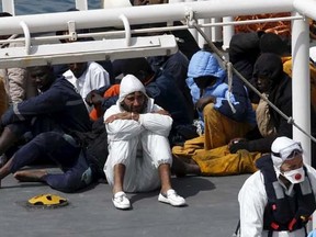 Mohammed Ali Malek (C, in white), one of two survivors of Saturday's migrant boat disaster, later arrested on suspicion of people trafficking, is seen watching bodies of dead migrants being disembarked from the Italian coastguard ship Bruno Gregoretti in Senglea in Valletta's Grand Harbour April 20, 2015. 
REUTERS/Darrin Zammit Lupi