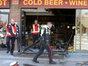 Police remove the front door of the Liquor Depot on 18th street in SE Calgary, Alta. as they investigate the scene of a smash and grab at that location on Tuesday April 21, 2015. A suspect in the attempted break-in was dropped off at the Rockyview General Hospital  at about 5:30 a.m. in life threatening condition after it is believed he was run over during the attempted robbery. (Stuart Dryden/Postmedia Network)