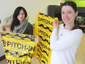 Sustainable Kingston volunteer Alia Tulloch, left, and projects and outreach co-ordinator Marta Reczek hold up the special garbage bags to be used by participants in Friday's annual Pitch-In community volunteer clean-up of the city. (Michael Lea/The Whig-Standard)