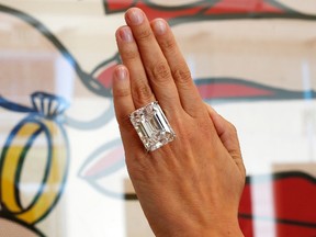 A woman displays a 100.20-carat diamond ring in front of Roy Lichtenstein's 1962 painting "The Ring (Engagement)" at a pre-auction viewing at Sotheby's in Los Angeles, California, in this file photo taken March 25, 2015.  The diamond is the highlight of a magnificent jewels sale in New York on Tuesday and could sell for up to $25 million, Sotheby's auction house said.  REUTERS/Lucy Nicholson/Files