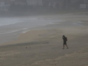 A man walks into a strong wind which stripped Sydney's Bondi Beach of tons of sand as heavy winds blow it inland, April 21, 2015.  REUTERS/Jason Reed