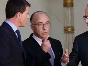 French President Francois Hollande (R) speaks with Interior minister Bernard Cazeneuve (C) and Prime Minister Manuel Valls at the end of the weekly cabinet meeting at the Elysee Palace in Paris, April 22, 2015. French police have detained a man they suspect of planning an imminent armed attack on one or two churches, the interior minister said on Wednesday.  REUTERS/Philippe Wojazer